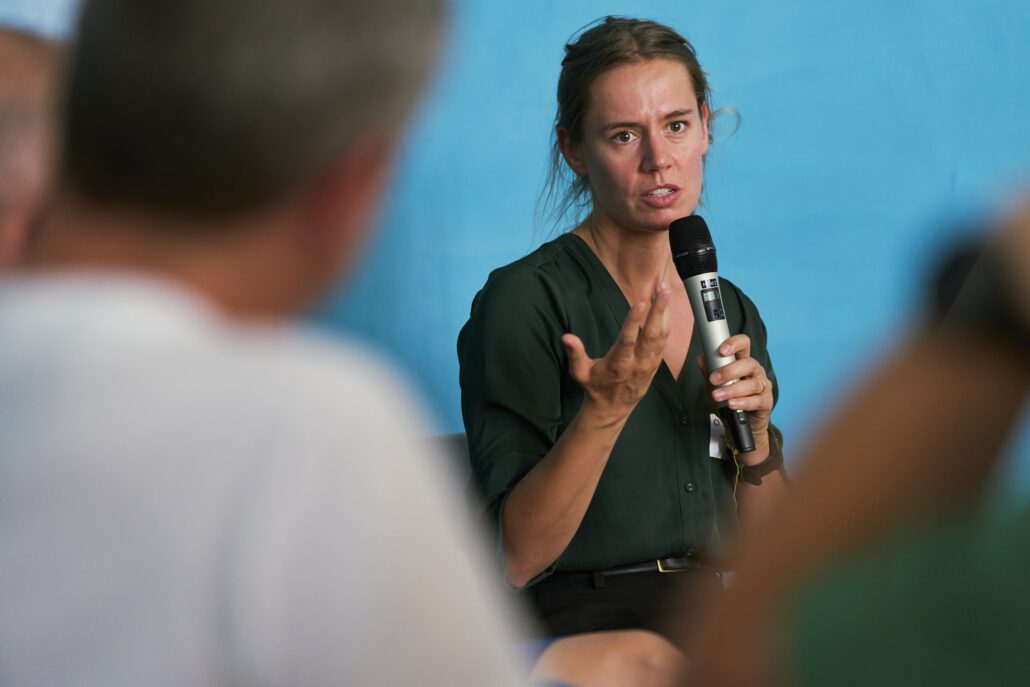 Prof. Dr. Anna Lene Seidler spricht beim Methodenforum in eine Mikrofon, vor ihr sitzen unscharf erkennbar Teilnehmer*innen. Foto: CDS